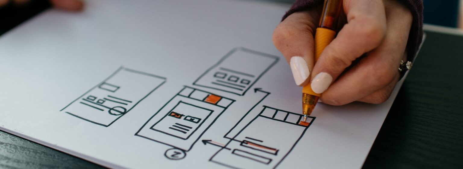 UI en UX design voorbeeld: persoon tekent wireframes met een stift op papier